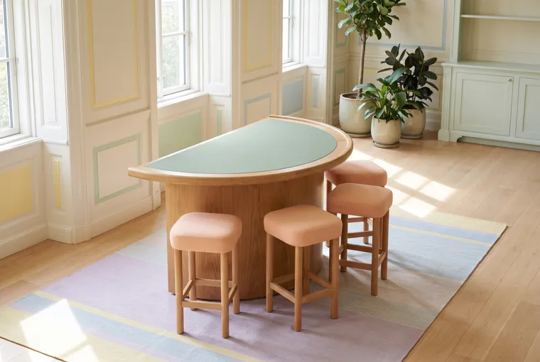 Illustration: an empty card table with a plain green felt top and stools tucked in, in a bright room before opening.